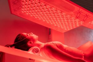 A female SUMA Life House guests lies on the Ammortal Chamber bed. She's placed the nasal cannula around her nose to incorporate hydrogen inhalation therapy for the best red light bed treatment in Greenwich, CT.